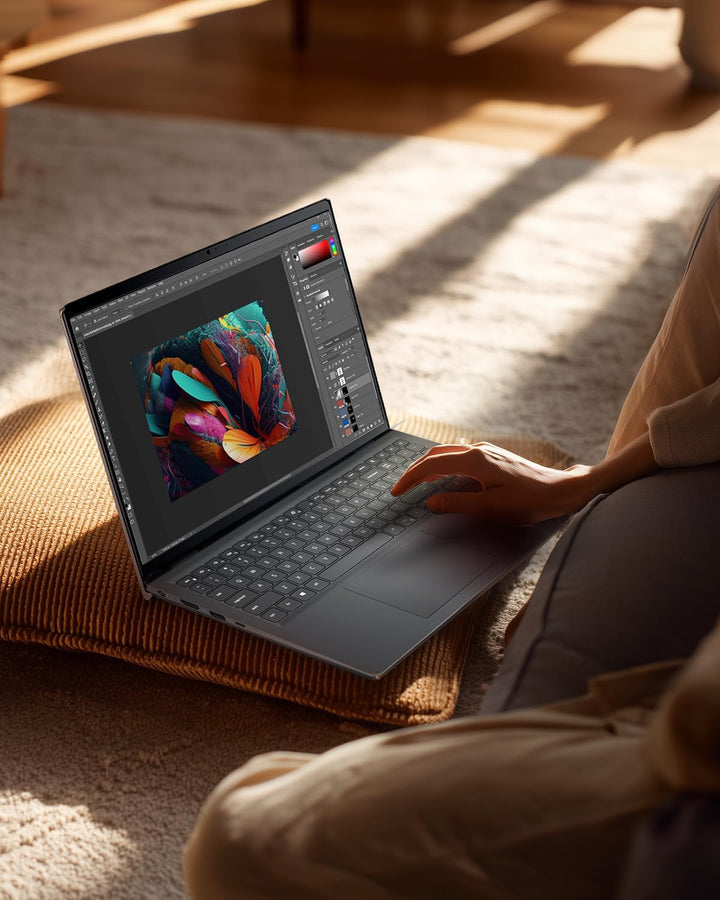 Person using a laptop with a colorful design on the screen in a cozy indoor setting.