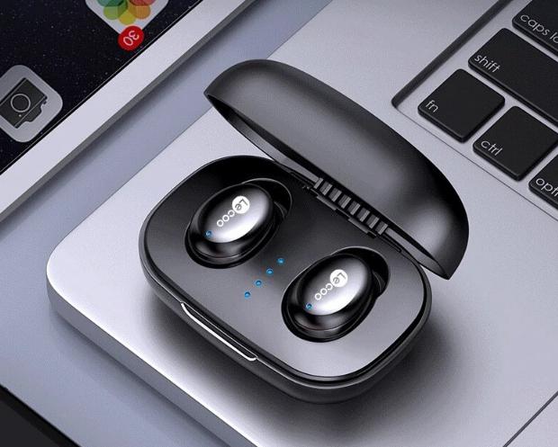 Black wireless earbuds in a charging case on a laptop keyboard