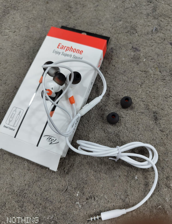 Earphones with packaging on a sandy surface